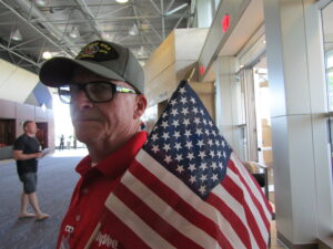 Jeff Ostrand of Bettendorf holds an American flag as he greets veterans at a previous Honor Flight of the Quad Cities’ pre-flight dinner. CREDIT DAVE THOMPSON