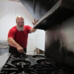 Todd Herzog, one of the owners of the Life Breads Gluten-Free Bakery at 1509 N. Harrison St., Davenport, cleans a stove in the storefront