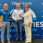 Ryan Carlson accepts the Carol J. Mindrup Award for outstanding volunteer service to the TBK Bank QC Marathon from founding race director Joe Moreno (left) and board member Tamia Keppy (right).
