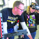 David Hull, a welding instructor at Black Hawk College, helps Azzy Thacher, 13, with a virtual welding exercise on Friday, March 6, during the Women in Manufacturing Summit at Black Hawk in Moline. CREDIT DAVE THOMPSON