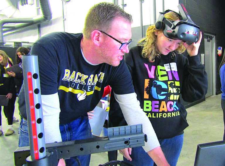 David Hull, a welding instructor at Black Hawk College, helps Azzy Thacher, 13, with a virtual welding exercise on Friday, March 6, during the Women in Manufacturing Summit at Black Hawk in Moline. CREDIT DAVE THOMPSON