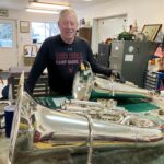 Lee Stofer with two of his restored tubas in his instrument shop in Camanche. CREDIT JONATHAN TURNER