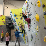 Rockhouse Nick Perreault (in blue) stands on the floor as his children tackle a climbing wall. He is pursuing a new startup business Rockhouse Quad Cities, which would be the first climbing gym in the QC region. CREDIT NICK PERREAULT
